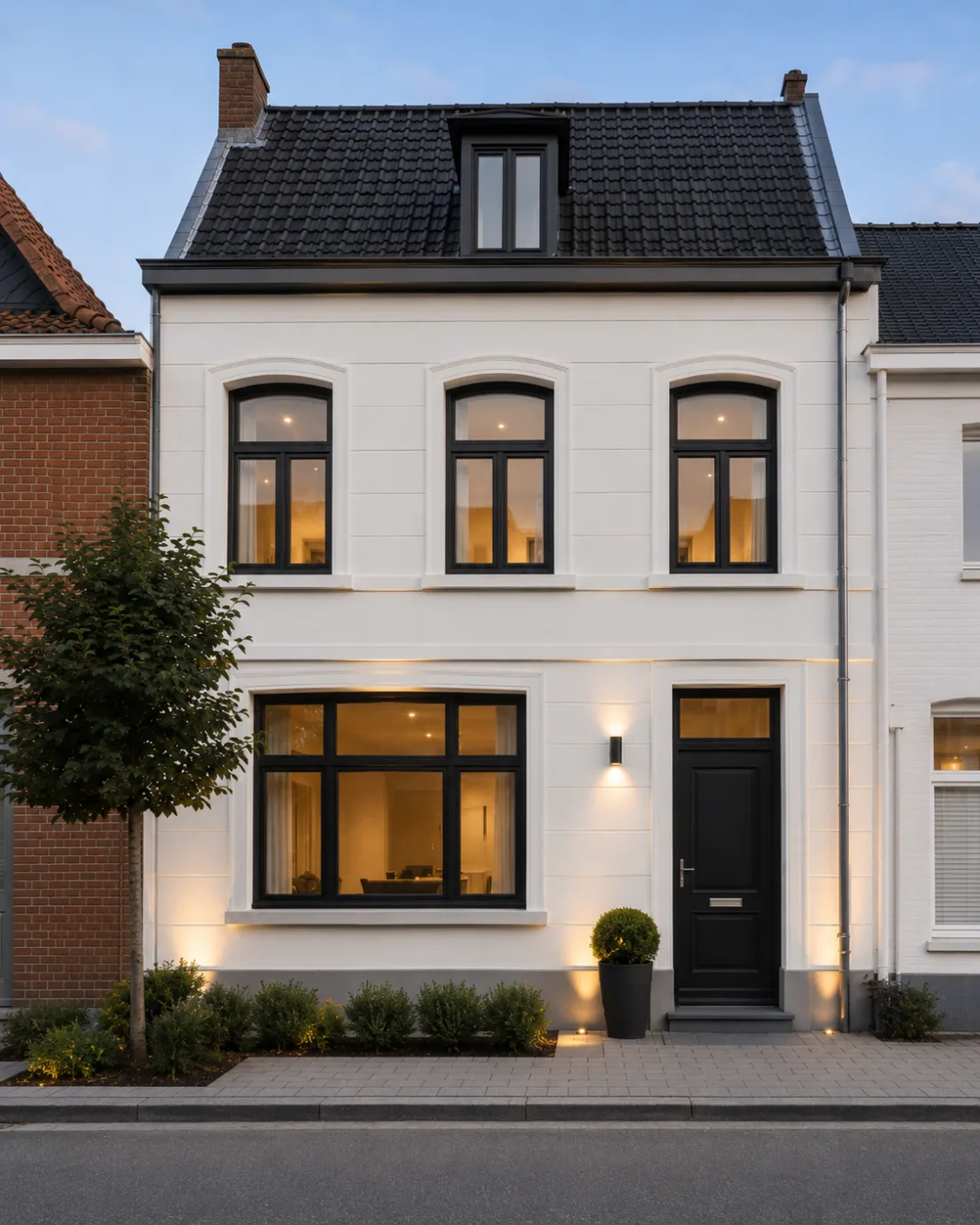 Dezelfde rijwoning met nieuwe witte gevel en zwarte ramen, na de renovatie